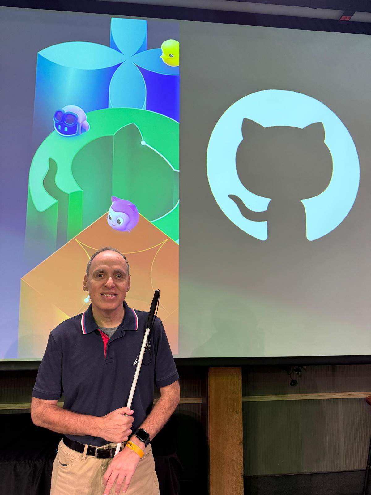 posando junto a una pantalla con el logo de GitHub.